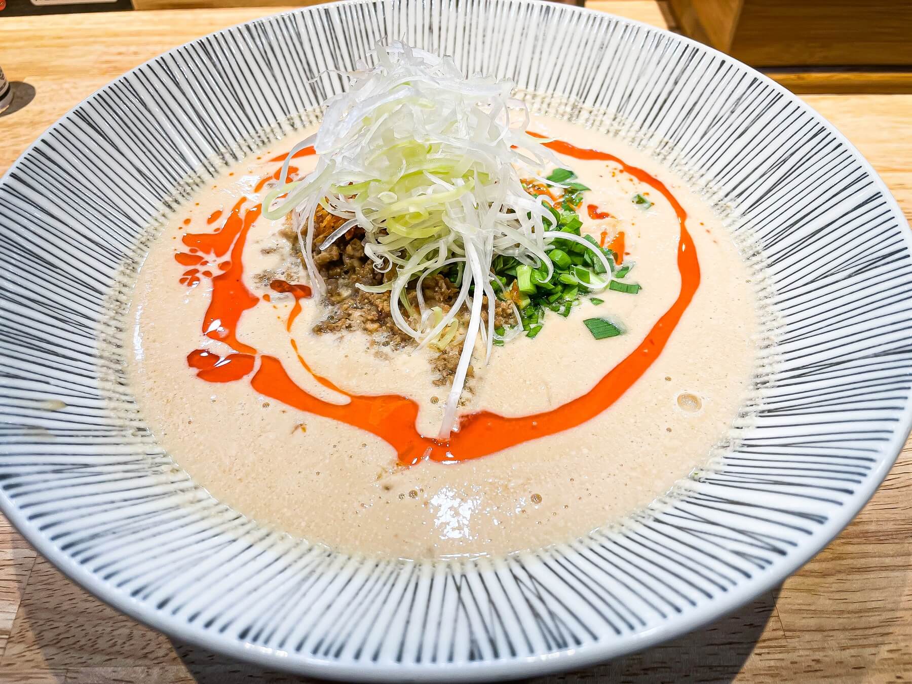 スタンダードな坦々麺のスープはゴマの香りと濃厚な味わいに重点を置き、香港由来の極細龍髭麺