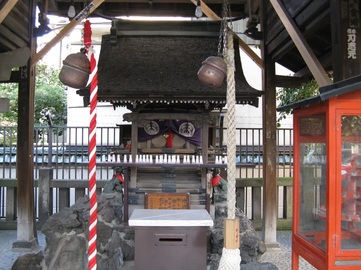 覆屋に守られた被官稲荷神社の木造社殿と狐の像