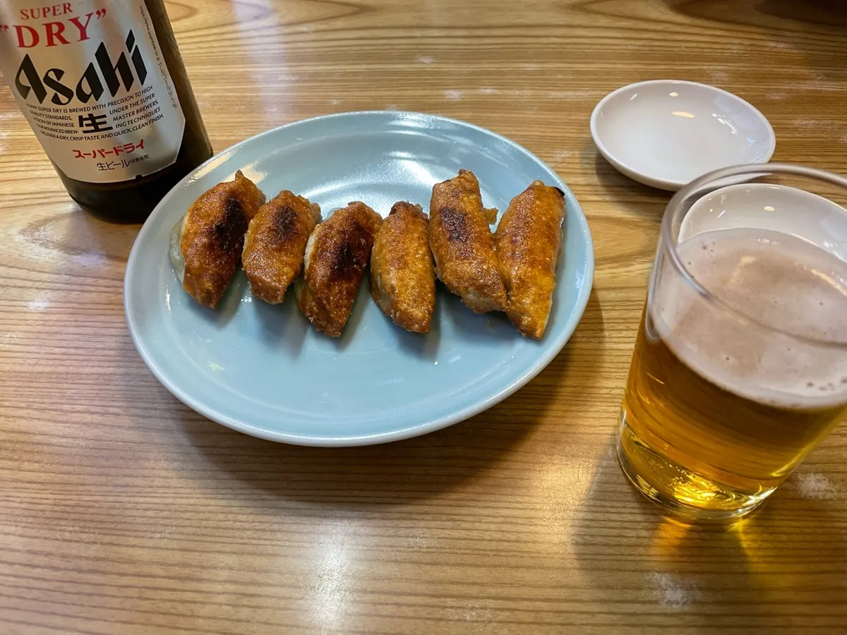 餃子の王さまの六つの餃子と、瓶ビール、ビールを注いだグラス