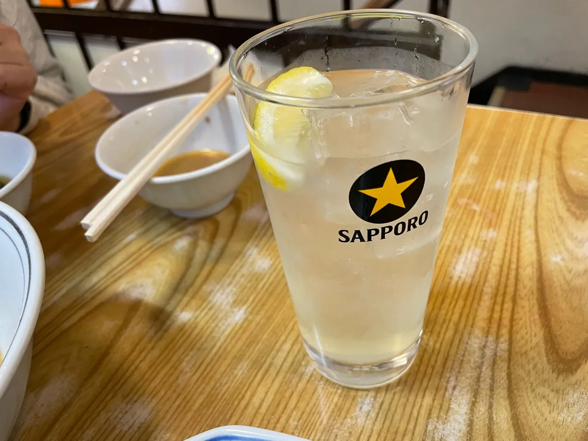 餃子の王さまの木のテーブルに置かれた、レモンと氷入りのドリンク