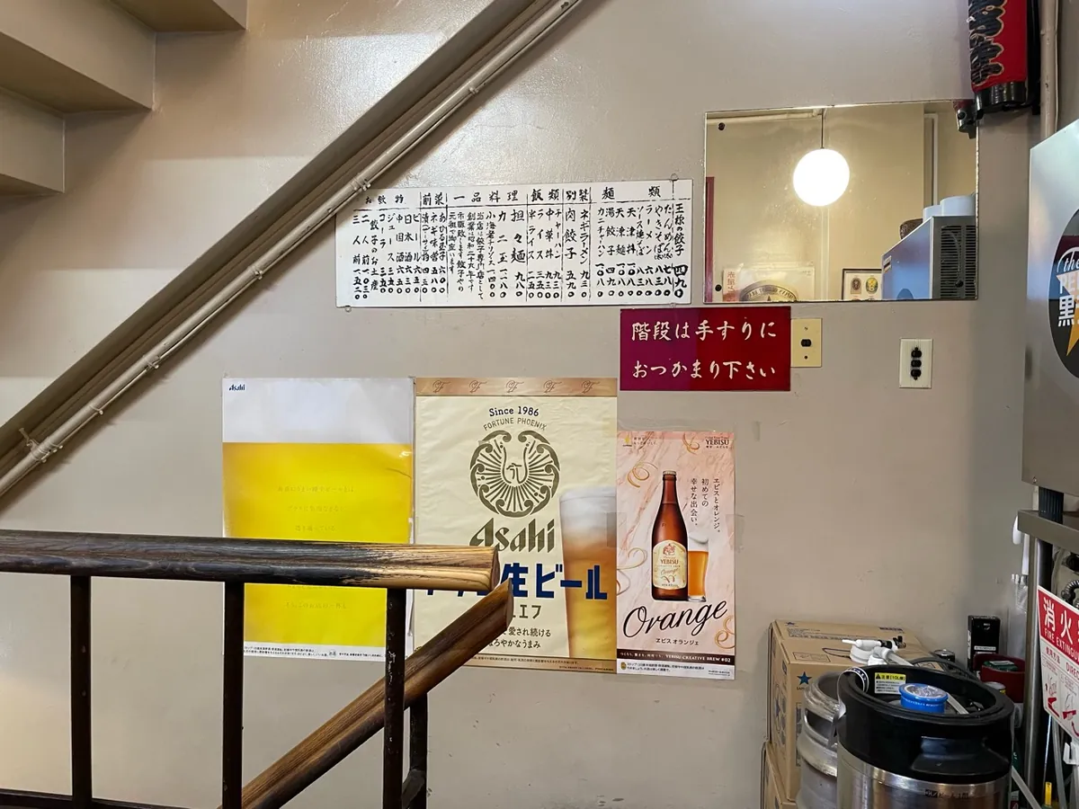 餃子の王さまの店内の階段、壁の料理メニューと手すりの案内