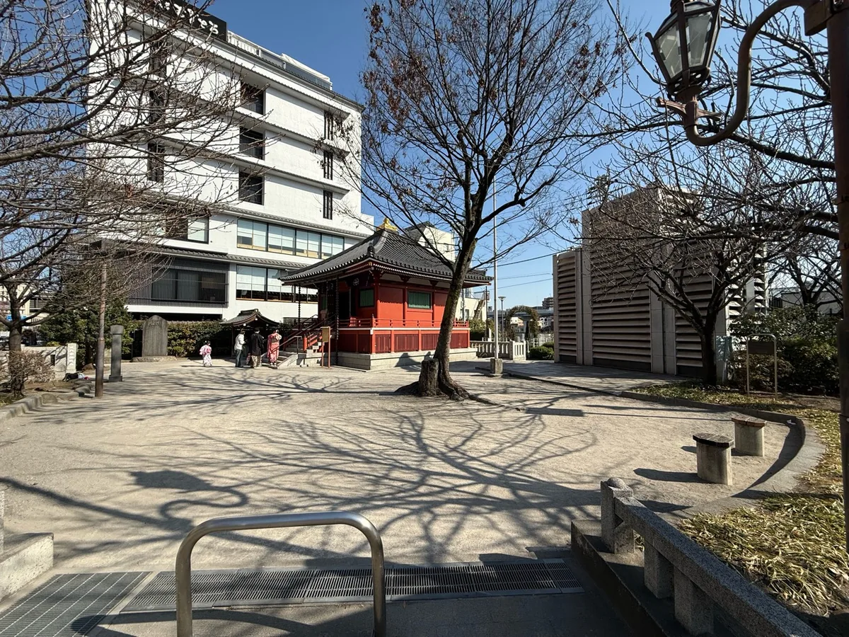 駒形橋の脇に建つ朱色の駒形堂と木々や石碑のある境内