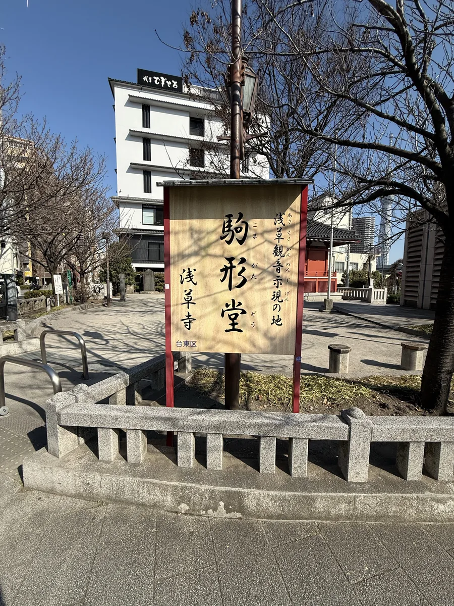 「浅草観音示現の地 駒形堂 浅草寺」と書かれた案内板と奥に見える朱色のお堂