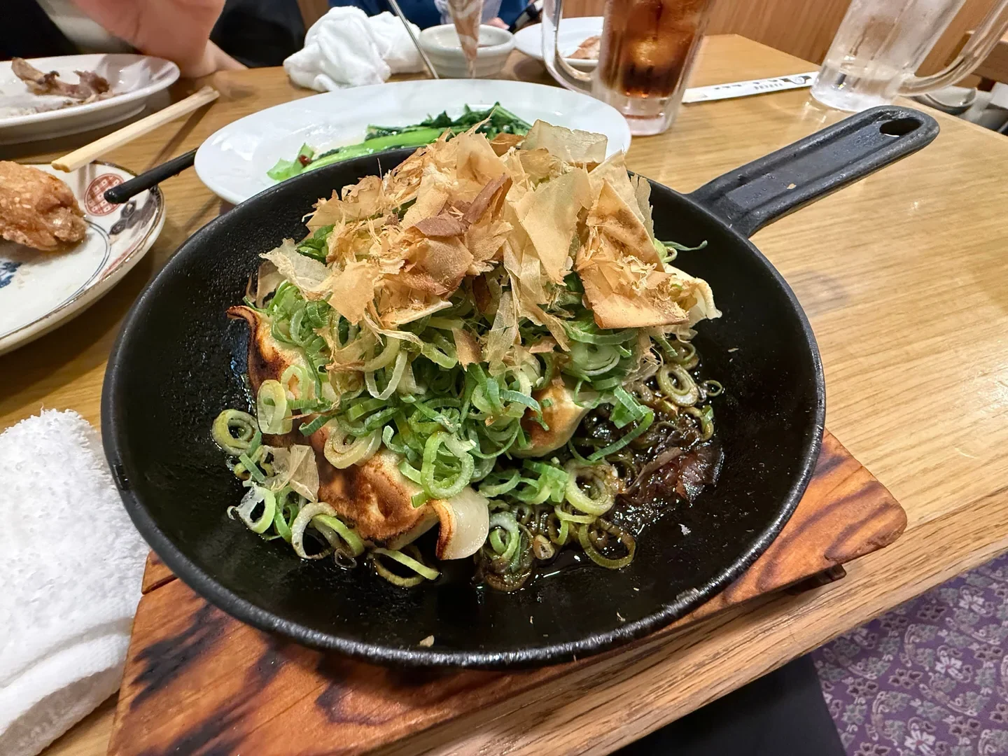 鉄鍋の餃子に盛られたたっぷりのねぎとかつお節