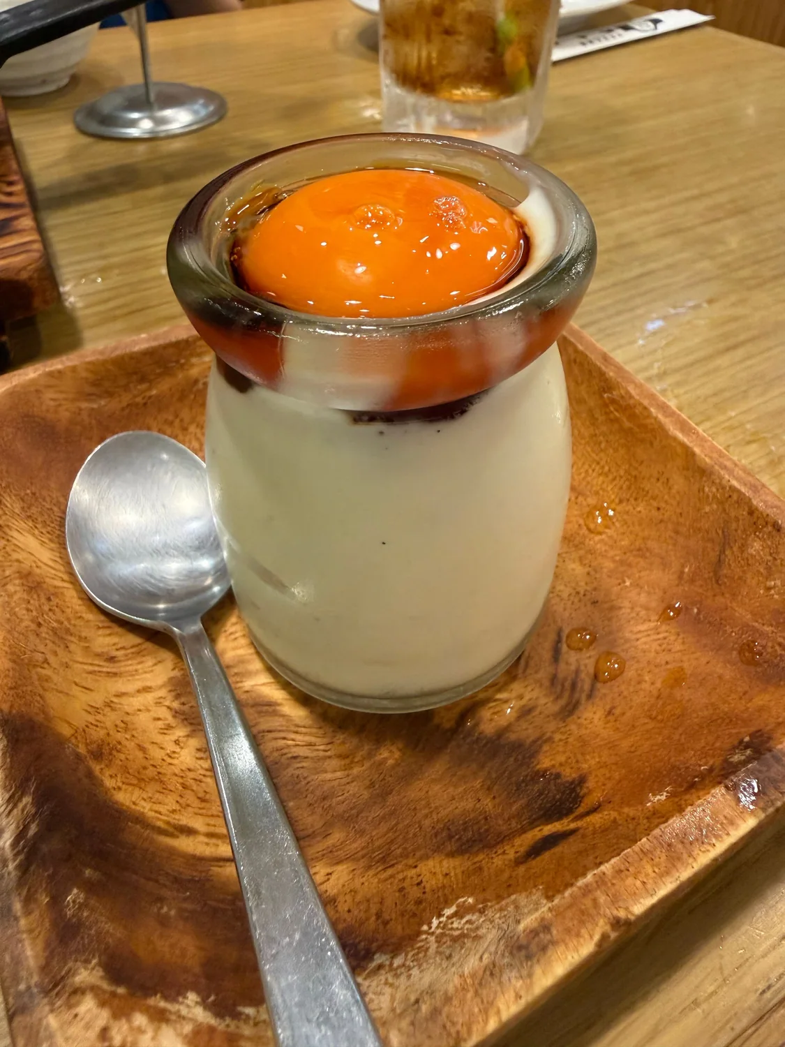 ガラスの容器に入った、鮮やかな黄色いトッピングのプリン