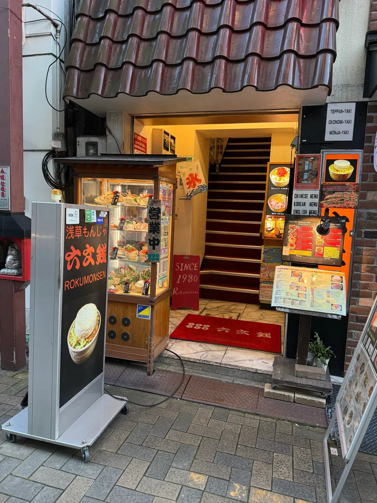 六文銭本店の入口。店名看板と食品サンプル、2階へ続く階段