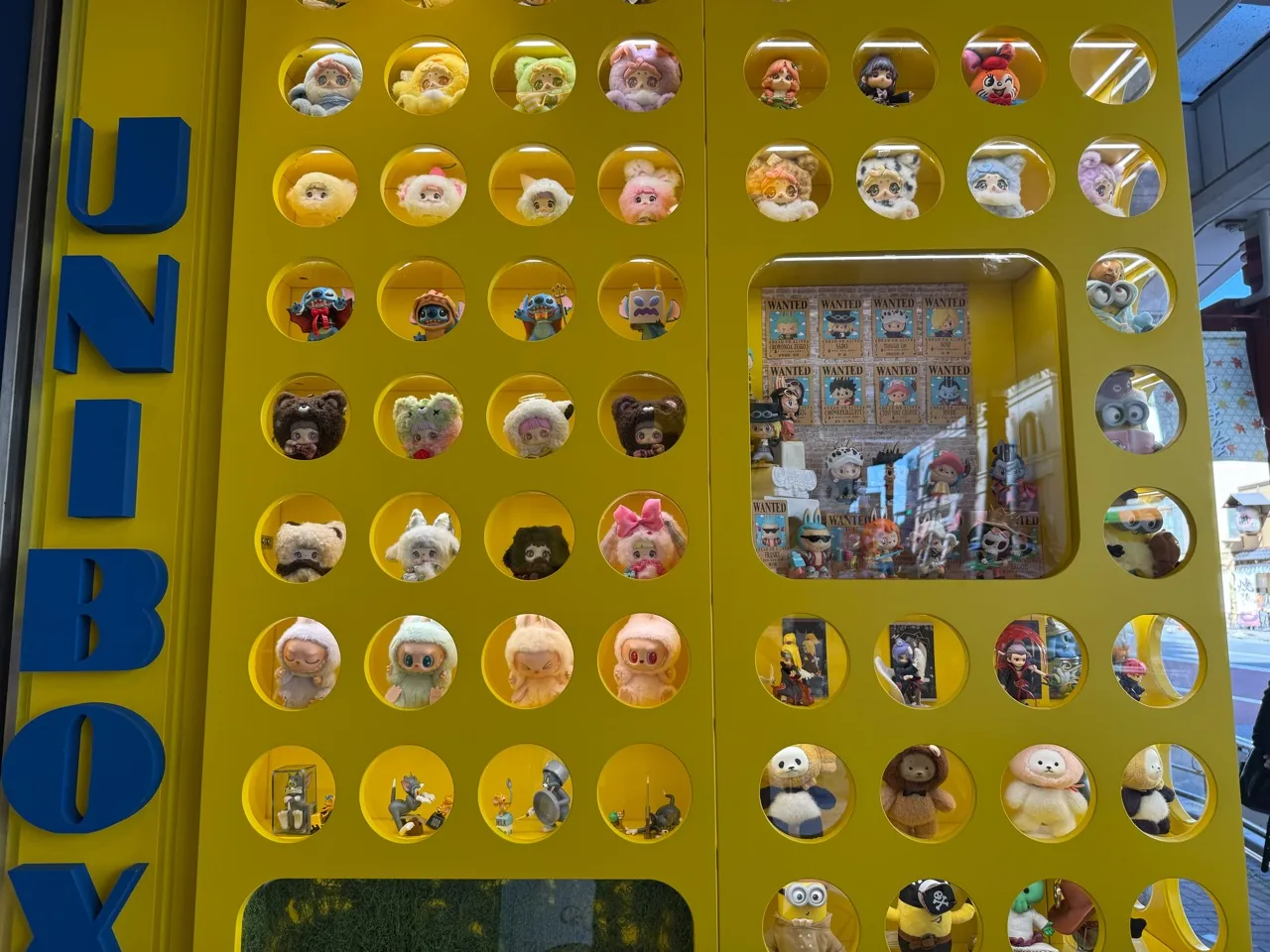 UNIBOX浅草の黄色い窓に並ぶぬいぐるみとキャラクター商品